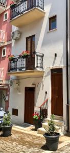 - un bâtiment avec 2 balcons et des fleurs en pots dans l'établissement I MORI - Holiday Rooms, à Lascari