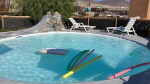 a swimming pool with surfboards and two chairs and a slide at Alojamiento Portofino Chañaral. in Ciudad de Chañaral