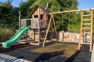 a wooden playground with a slide and swings at Entspannungsoase - Insel Krk in Rasopasno