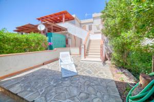 a white chair sitting on a stone patio with stairs at Corsaro Azzurro Apartment in Stintino