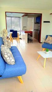 a living room with a blue couch and a kitchen at Apartamento San José in Melgar
