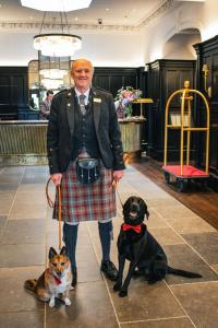 a man in a kilt standing next to two dogs at Cameron House on Loch Lomond in Balloch