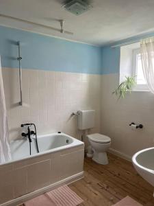 uma casa de banho com uma banheira, um WC e um lavatório. em Charming historical farmhouse em Finning