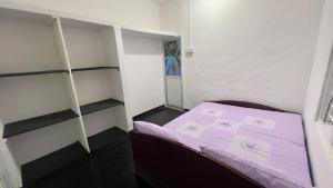 ニラヴェリにあるCoconut Leaf Shadow Guestの小さなお部屋で、紫のシーツが敷かれたベッド1台が備わります。