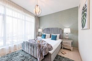 a bedroom with a large bed with blue pillows at Nasma Luxury Stays - Pastel-Colored Apt With Jaw-Dropping Marina Views in Dubai