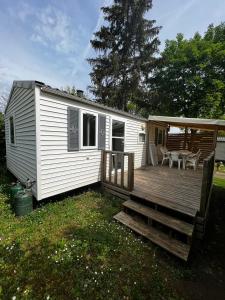ein weißes, kleines Haus mit einer Holzterrasse in der Unterkunft Mobil Home Cosi pour 6 (Camping Tohapi) in Vogelgrun