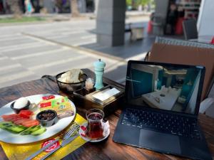 un ordinateur portable assis sur une table avec une assiette de nourriture dans l'établissement The Sea Front Boutique Hotel, à Antalya