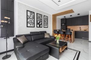 a living room with a black couch and a kitchen at Lux Wellness Resort & SPA Apartments by the River by Renters Prestige in Dziwnów