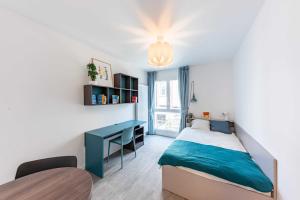 Schlafzimmer mit einem blauen Bett und einem Schreibtisch in der Unterkunft Cute Studio close to Paris - 1P - 509 in Ivry-sur-Seine