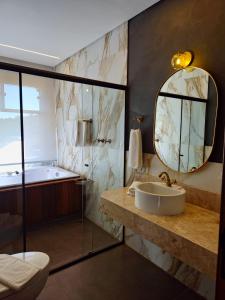 a bathroom with a tub and a sink and a mirror at Hotel Villa Greenberg in Monte Verde