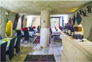 un restaurante con mesas, sillas y botellas de vino en Arnovalley Hotel en Urgup