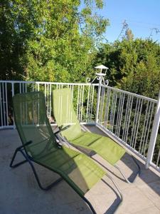 dos sillas verdes sentadas en un porche junto a una valla en Jonzac Centre Ville - Private Home near Chateau, en Jonzac