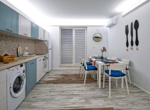 een keuken met een tafel en stoelen en een keuken met blauwe kasten bij GUEST HOUSE RHEA / КЪЩА ЗА ГОСТИ РЕЯ in Balchik