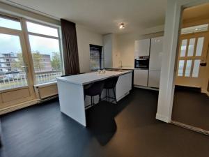 a kitchen with a white island in a room with windows at k50159 Spacious and modern apartment near the city center, free parking in Eindhoven