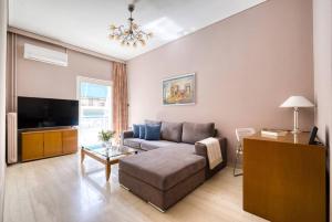 uma sala de estar com um sofá e uma televisão em Μοντέρνο διαμέρισμα 2' από το μετρό em Atenas