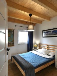a bedroom with a bed with a blue comforter and a window at Domki Trzy - 2 in Smołdziński Las