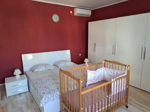 una camera da letto con una culla e una parete rossa di Apartments Balen a Rab