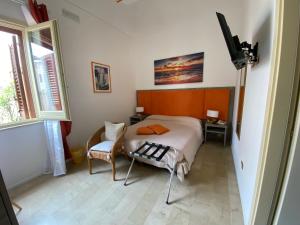 a bedroom with a bed and a chair and a television at Albergo Bouganville in Favignana