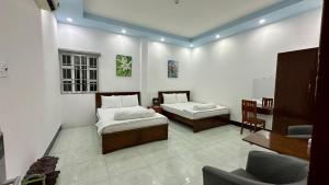 Cette chambre comprend deux lits, une table et une chaise. dans l'établissement Khách sạn Anh Tuấn, à Bạc Liêu