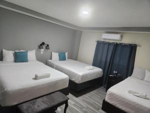 2 łóżka w małym pokoju z niebieskimi zasłonami w obiekcie Mi Tierra Hotel y Restaurante w mieście San Luis