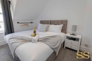sypialnia z dużym łóżkiem z białą pościelą i stolikiem nocnym w obiekcie Pearl Penthouse - 1 MINUTE FROM 02 ACADEMY - FREE PARKING - 5 MINUTES FROM THE BEACH - FAST WI-FI - SMART TV w Bournemouth