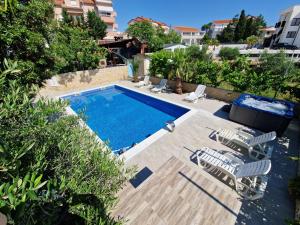 a swimming pool with two lawn chairs and a swimming pool at Pool Apartment Knezevic in Novalja