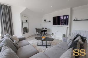 a living room with a couch and a table at Pearl Penthouse - 1 MINUTE FROM 02 ACADEMY - FREE PARKING - 5 MINUTES FROM THE BEACH - FAST WI-FI - SMART TV in Bournemouth