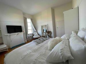 a large white bed in a room with a tv at The Grayce Place. in Warrnambool
