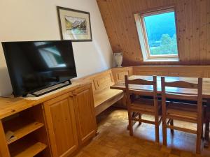 a dining room with a television and a table and a window at BovecApartmentA in Bovec