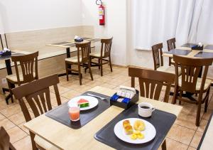 a dining room with tables and chairs with plates of food at Europa Hotel Brasília by Bsb Inn in Taguatinga +40 photos