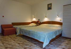 1 dormitorio con 2 camas y 1 silla en Family Hotel Orfei, en Nesebar