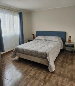 een slaapkamer met een bed met een blauw hoofdeinde bij Alojamiento El Cóndor in Esquel
