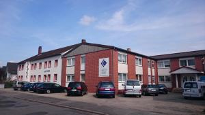 a large brick building with cars parked in a parking lot at Dill Apartments Ilsede in Ilsede