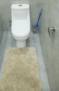 a bathroom with a white toilet and a rug at JC Apartments in Ndola