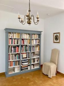 een boekenplank gevuld met boeken naast een stoel bij Lady Blue, villa à 15 mn plage à pied, parking, wifi, jardin in La Grande-Motte