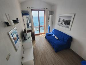 a living room with a blue couch and a balcony at House Grecale in Moneglia