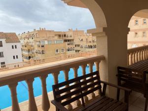a balcony with a bench looking out at the city at Apartamento Portofino Golf & Puerto Almerimar in Almerimar