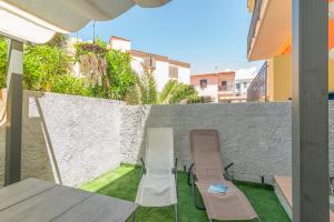 d'une terrasse avec 2 chaises, une table et un mur. dans l'établissement Loriana seaside home, à Santa Teresa Gallura