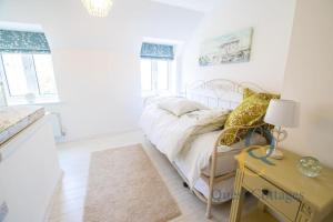 a white bedroom with a bed and a yellow table at 23 By The Sea - Modern Beach Apartment for 1 pet in Camber