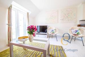 a living room with two chairs and a tv at 23 By The Sea - Modern Beach Apartment for 1 pet in Camber