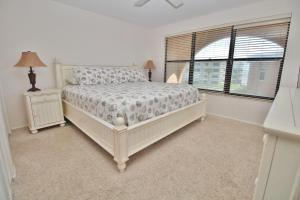 a white bedroom with a bed and a window at Ocean Club North C208 in New Smyrna Beach