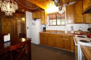 a kitchen with wooden cabinets and a white refrigerator at Canyon Cabin - A quaint cabin in a peaceful location yet close to Big Bear's attractions! in Fawnskin