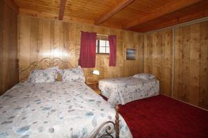 a bedroom with two beds in a room with wooden walls at Canyon Cabin - A quaint cabin in a peaceful location yet close to Big Bear's attractions! in Fawnskin