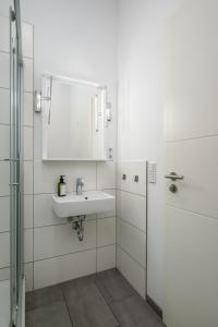 La salle de bains blanche est pourvue d'un lavabo et d'un miroir. dans l'établissement Apartments an der Arena Leipzig, à Leipzig