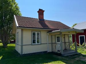 mały żółty dom z czerwonym dachem w obiekcie Stuga i centrala Älvdalen w mieście Älvdalen