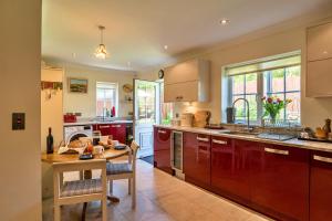 een keuken met rode kasten en een houten tafel bij Finest Retreats - Seascape in Teignmouth