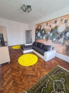 - un salon avec un canapé et un tapis jaune dans l'établissement Mural Art Apartament, à Petroşani