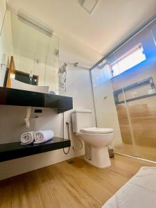 a bathroom with a toilet and a glass shower at Lara's Hotel in Capitólio