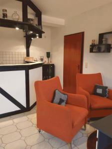 eine Küche mit zwei orangenen Stühlen und einer Theke in der Unterkunft Ferienwohnung Pentagono in Engelskirchen