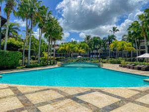 a swimming pool with palm trees and a bridge at Xeliter Balcones del Atlantico - Las Terrenas in Las Terrenas